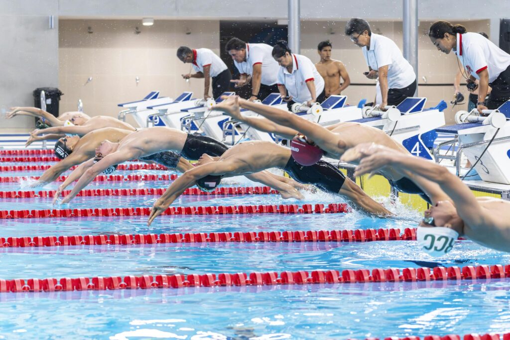 Swimmers gracefully dive into the pool, marking the start of a competitive race.